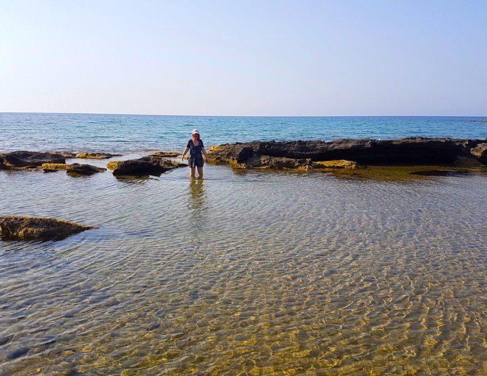 JJ standing in the sea in Northern Cyprus. there is blue sky and rocks sticking out of the sea. the water is clear and you can see to the bottom of the sea floor.
Cyprus instagram captions
