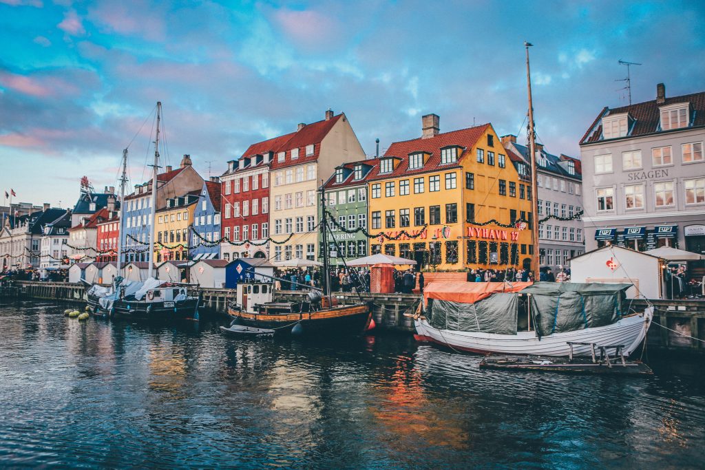 Copenhagen, Denmark. There are boats moored to the riverside and colourful buildings in the background 