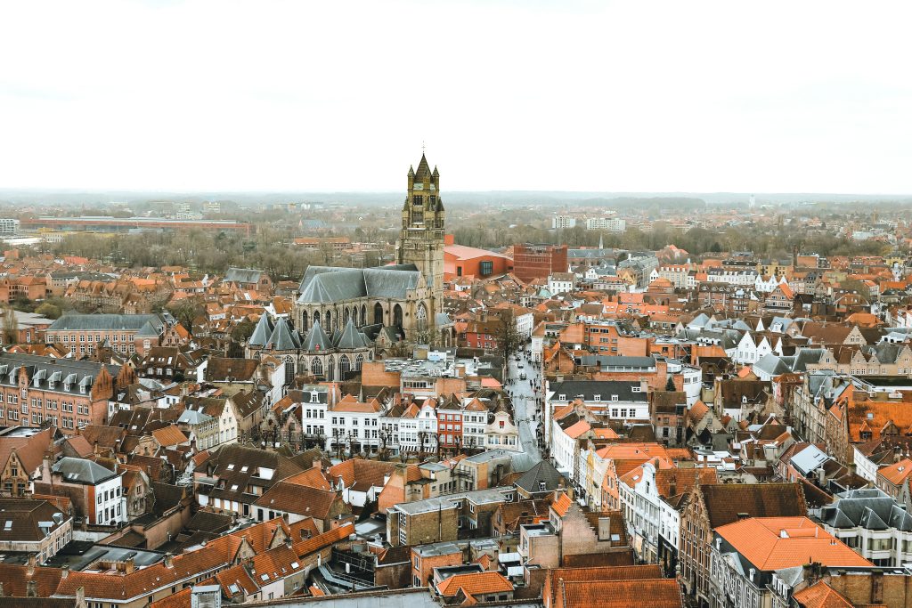 An aerial view looking over the rooftops of Brugge, Belgium. A large church stands in the middle