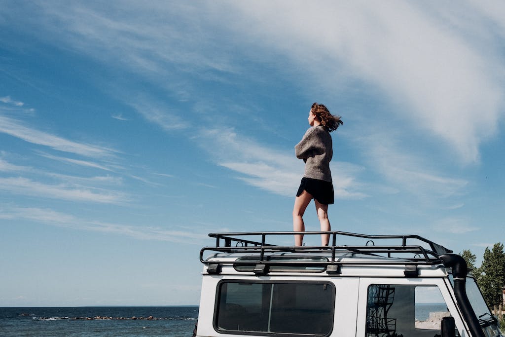 Woman Standing on Top of a Car