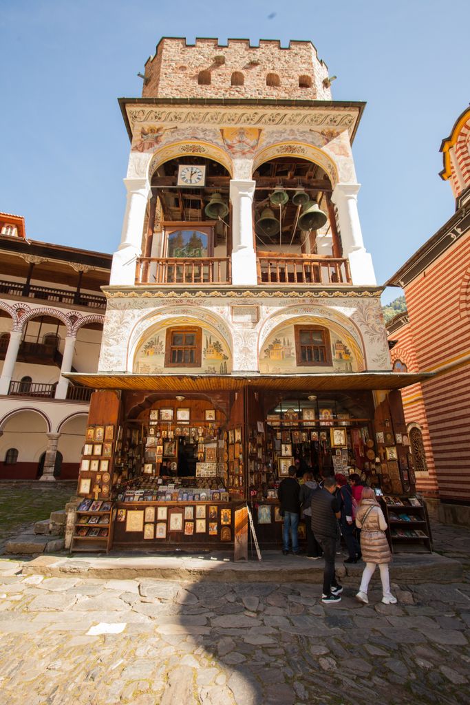Vertical view of Rila Monastery bell tower and souvenir shop on a sunny day. Bulgaria Instagram Captions